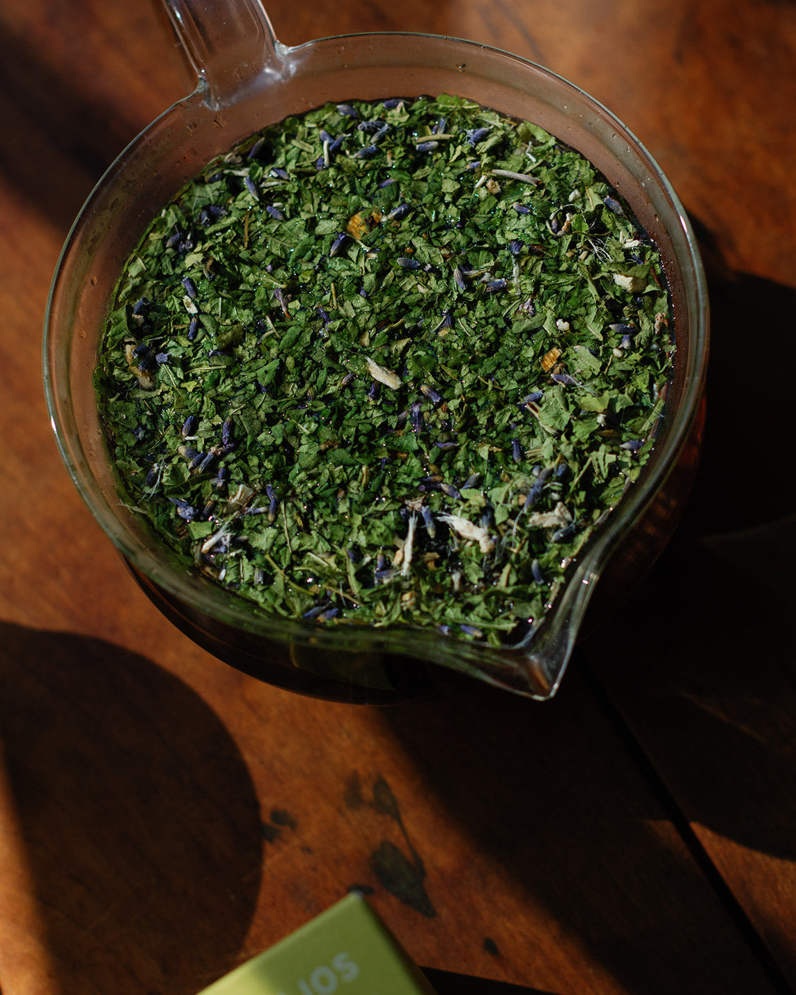 Glass teapot filled with Helios herbal tea  on a wooden surface
